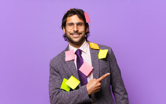 young handsome indian man smiling cheerfully, feeling happy and pointing to the side and upwards, showing object in copy space. humorous business concept
