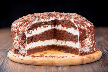 Cut of puff chocolate cream cake sprinkled with chocolate chips.