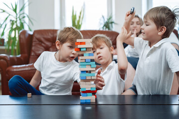 Leisure and relaxed lifestyle of caucasian family. Little brothers have fun and play board game competing at home.