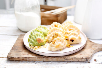 Close-up of dumplings, pierogi with chopped fried onion, on a white plate.