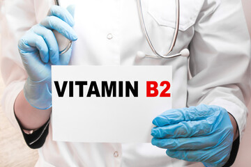The doctor's blue - gloved hands show the word VITAMIN B2 - . a gloved hand on a white background. Medical concept. the medicine