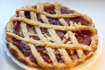 Baked sweet open cake with apricot jam on plate on white wooden background