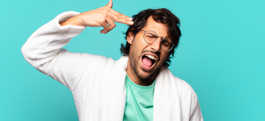 young handsome indian man looking unhappy and stressed, suicide gesture making gun sign with hand,...
