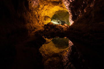 Optical reflection effect on cave lava tube illuminated in Canary Islands. Geological cavern formation, tourist attraction concepts