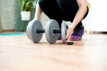 Fototapeta na wymiar person doing workout and put on a weght disc on a barbell dumbbell