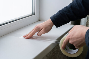 hands holding and a[[lying adhesive tape on the surface