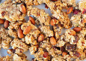 Close view of whole grains granola with fruit and nuts on a plate illuminated with natural light.