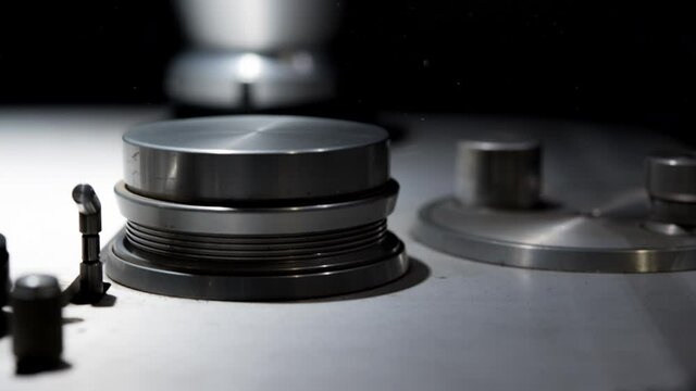 Panning close up on spools sprocket and head of vintage professional analog sound multitrack studio tape recording equipment