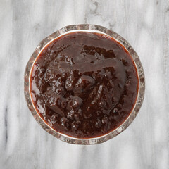 Bowl of plum butter on a gray marble tabletop top view.