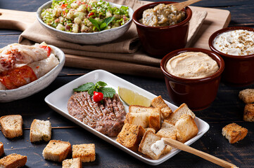 
Raw kibbeh, toast with Syrian curd, humus and babaganush in the background