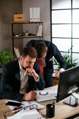 Two businessman discussing work and using computer in the office. Colleagues working in the office.