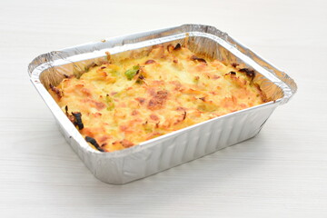 Baked chicken and mushroom cannelloni, bathed in cream in cheese sauce gratin on white wooden background