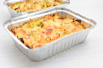 Baked chicken and mushroom cannelloni, bathed in cream in cheese sauce gratin on white wooden background