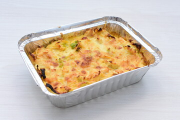 Baked chicken and mushroom cannelloni, bathed in cream in cheese sauce gratin on white wooden background