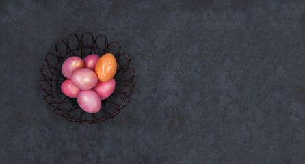 Concept of Easter holiday and spring. Banner. Easter multicolored pastel pink eggs in a metal basket on a dark background. Flat lay. Minimal style. Copy space