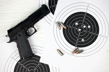 Gun and many bullets shooting targets on white table in shooting range polygon. Training for aiming and shooting