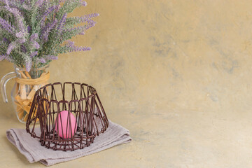 Happy easter. Spring holiday concept. Painted pink eggs in a metal basket on a light background. A bouquet of lavender in a vase. Still life. Copy space.