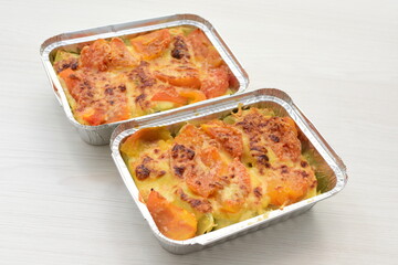 Baked chicken and mushroom cannelloni, bathed in cream in cheese sauce gratin on white wooden background