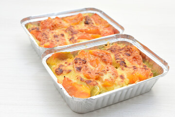 Baked chicken and mushroom cannelloni, bathed in cream in cheese sauce gratin on white wooden background