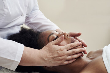 Obraz na płótnie Canvas Young woman having anti-stress facial massage in salon at spa resort. Face massage. Facial skin care. Woman at beauty spa salon