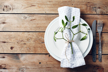 Table setting with white plates and mistletoe.