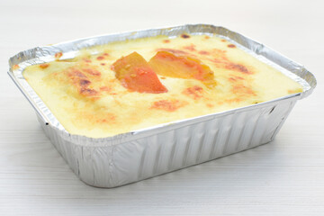Baked chicken and mushroom cannelloni, bathed in cream in cheese sauce gratin on white wooden...