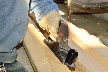 a man planes a wooden board with a tool - a planer