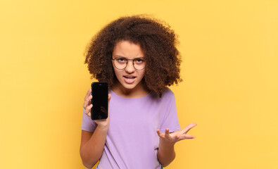 pretty afro teenager looking angry, annoyed and frustrated screaming wtf or what’s wrong with you...