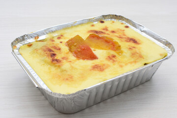 Baked chicken and mushroom cannelloni, bathed in cream in cheese sauce gratin on white wooden background