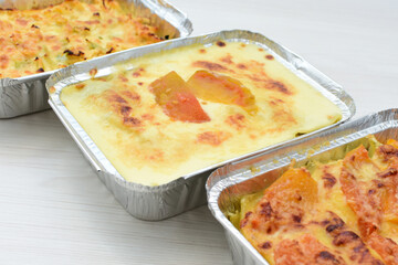 Baked chicken and mushroom cannelloni, bathed in cream in cheese sauce gratin on white wooden background
