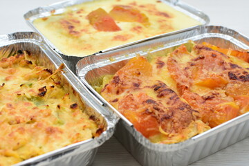 Baked chicken and mushroom cannelloni, bathed in cream in cheese sauce gratin on white wooden background