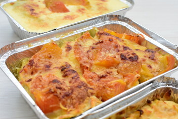 Baked chicken and mushroom cannelloni, bathed in cream in cheese sauce gratin on white wooden background