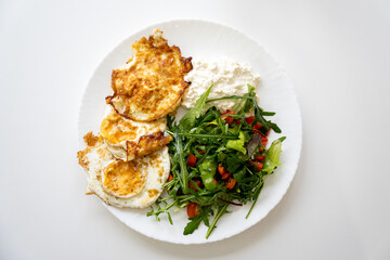 Brokastis uz balta galda baltā šķivī kur ir divas ceptas olas