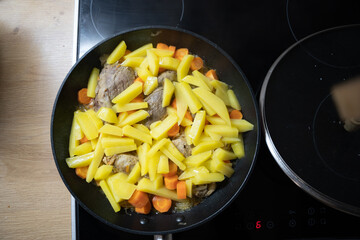 Potatoes, carrots and chicken were baked in a black pan