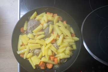 Potatoes, carrots and chicken were baked in a black pan