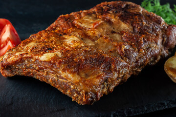 Grilled pork ribs, served on a graphite board with tomatoes