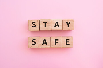 STAY SAFE - text on wooden cubes on pink background