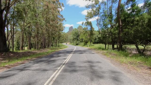 Rear facing driving point of view POV of a deserted Queensland country road with Glasshouse Mt Coonowrin - ideal for interior car scene green screen replacement