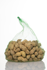 peanuts in a mesh bag on a white background, Organic peanuts isolated on a white background front view of a pile of peanuts close-up, selective focus.