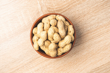 peanuts in a shell in a clay plate, organic peanuts isolated on a white background top view. A bunch of peanuts in close-up, selective focus.