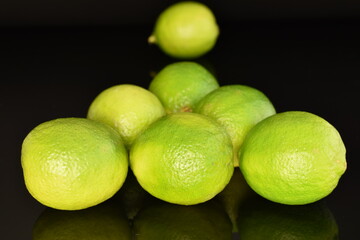 Several ripe limes, close up, on a black background.