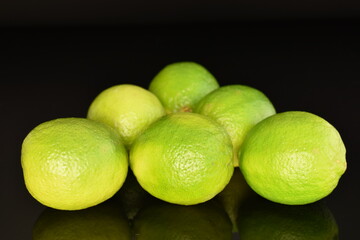 Several ripe limes, close up, on a black background.