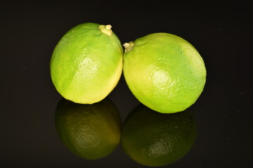 Fototapeta na wymiar Two ripe delicious limes, close-up, on a black background.