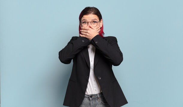 young attractive red hair woman covering mouth with hands with a shocked, surprised expression, keeping a secret or saying oops