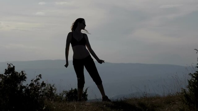 Silhouette of young woman dancing in the nature