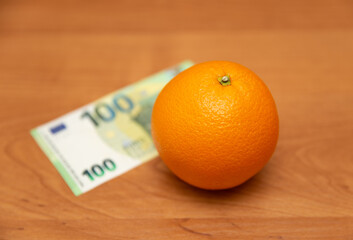 Orange and euro. The table is orange. 100 euro banknote. The 2013 design. A fruit. It contains a...