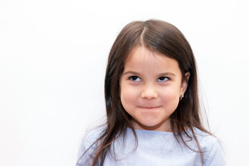 Little girl with dark hair and brown eyes smiles shyly on white background