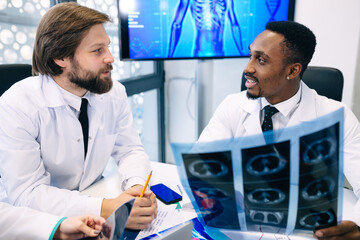 Fototapeta premium Two doctors look at x-rays and discuss the diagnosis. They sit a