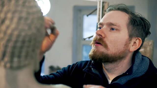 Concentrated artist working on Buddha statue face using a special tool at workshop