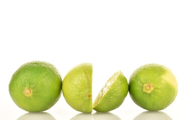 Two whole and two halves of green organic lime, on a white background.